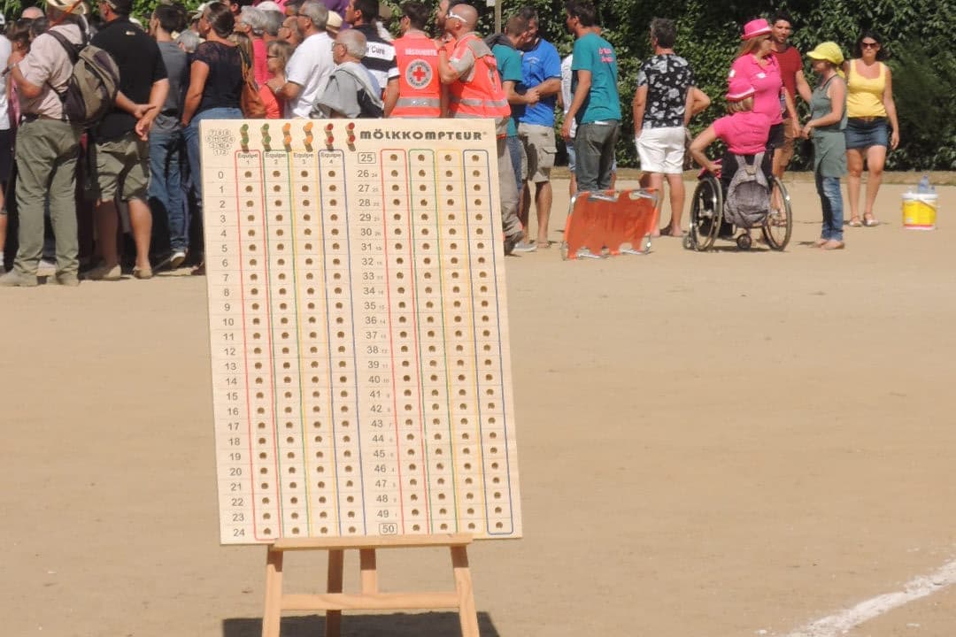 A large wooden peg scoreboard on an easel at a Mölkky tournament, with columns of holes numbered from 0 to 50 for four teams.